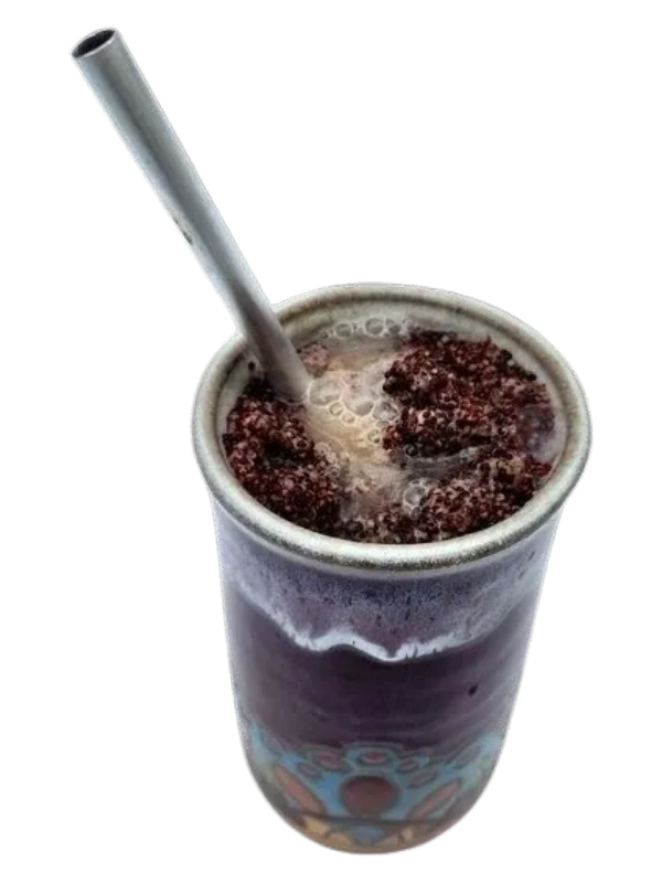 Ceramic tongba vessel filled with fermented millet and hot water, with a metal straw for drinking.