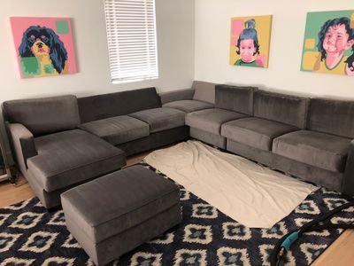Complete cleaning of a gray velvet sectional and colorful pictures on the wall.