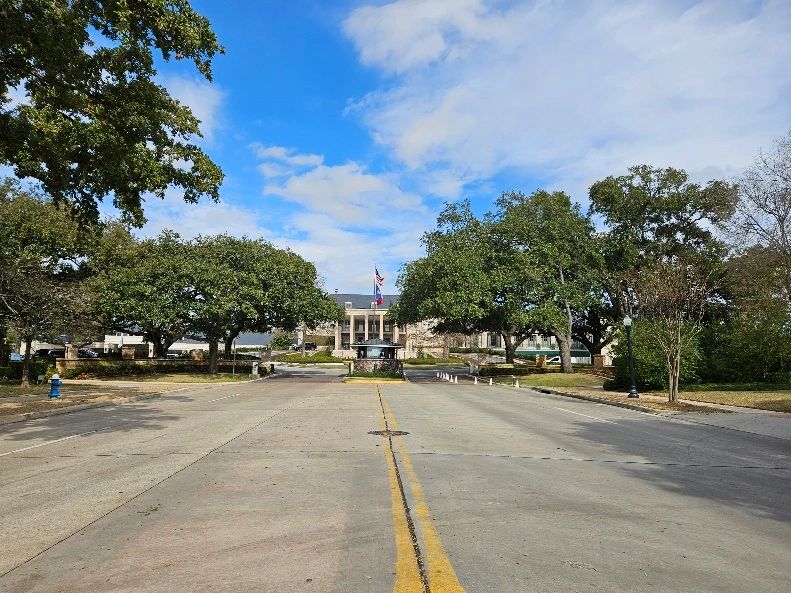 Clubhouse and front entrance gate to the River Oaks Country Club in Houston, Texas. Trees along road