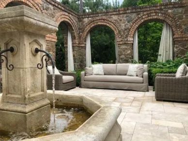 Restoration Hardware patio sofa and armchairs in an outdoor patio in front of a fountain.