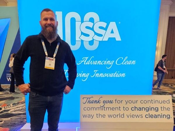 Justin from Simply Clean Upholstery Professionals in front of the ISSA convention sign in Las Vegas.