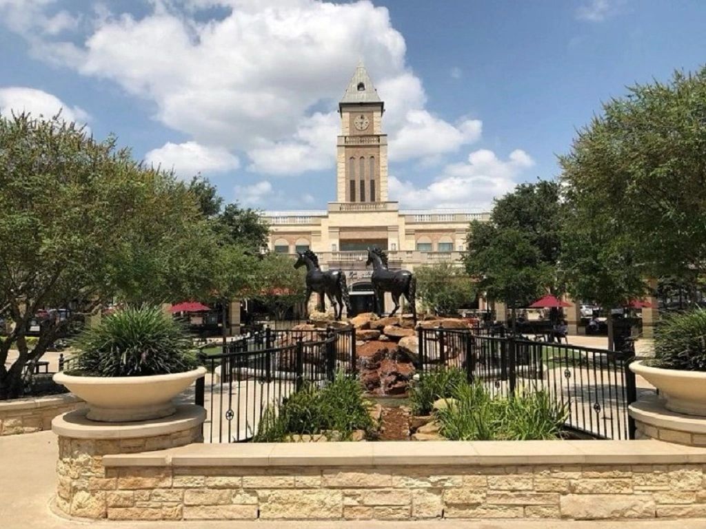 Two horse statues in front of a clock tower at the Sugar Land Town Square in Sugar Land, Texas.