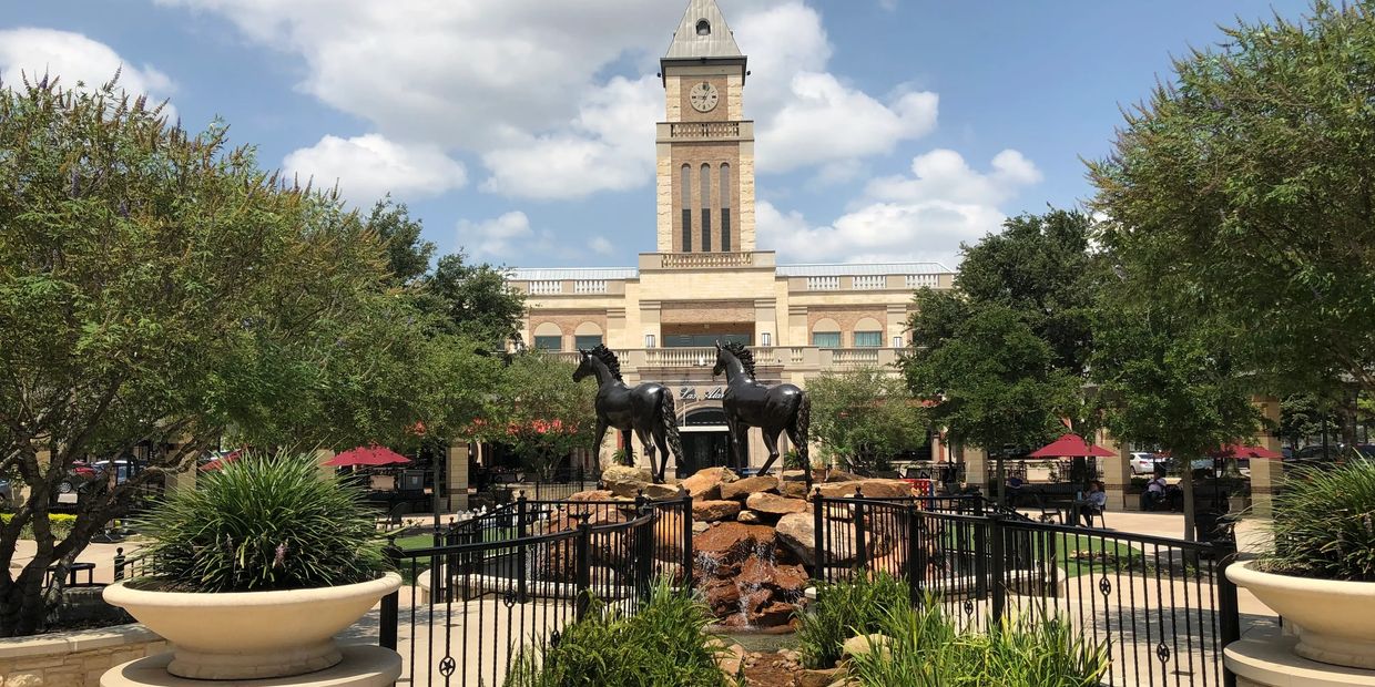 Two horse statues in front of a clock tower at the Sugar Land Town Square in Sugar Land, Texas.