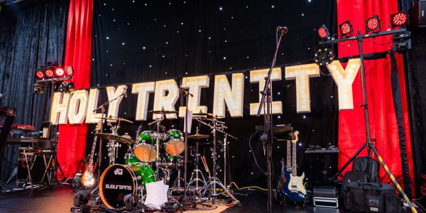 Drum set and band instruments with Holy Trinity lighted sign in the background