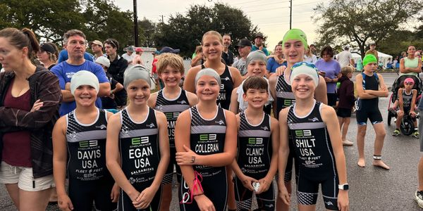 Young triathletes in matching uniforms posing before a race.