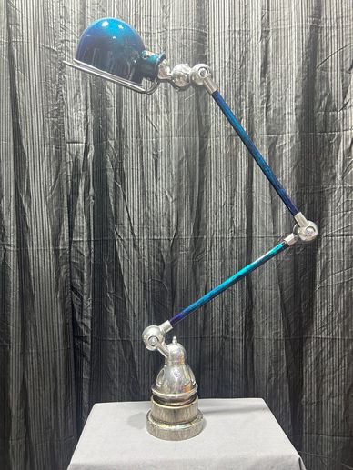 Lampe de bureau articulée bleue sur fond noir.