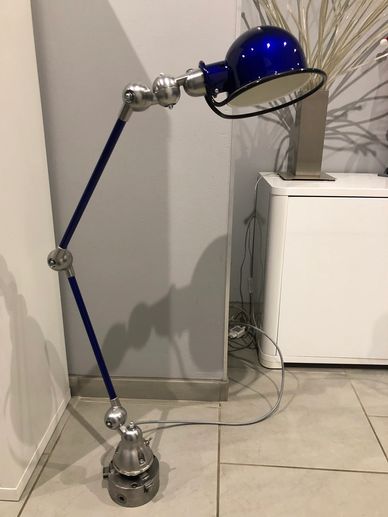 Lampe bleue articulée posée au sol.