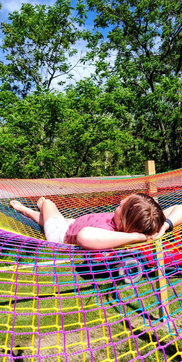 Person relaxing on a colorful hammock outdoors.