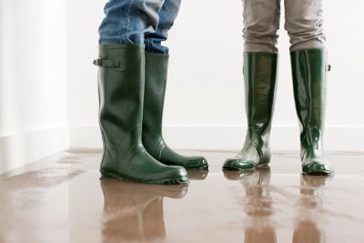 Two people wearing green rain boots on a wet floor.