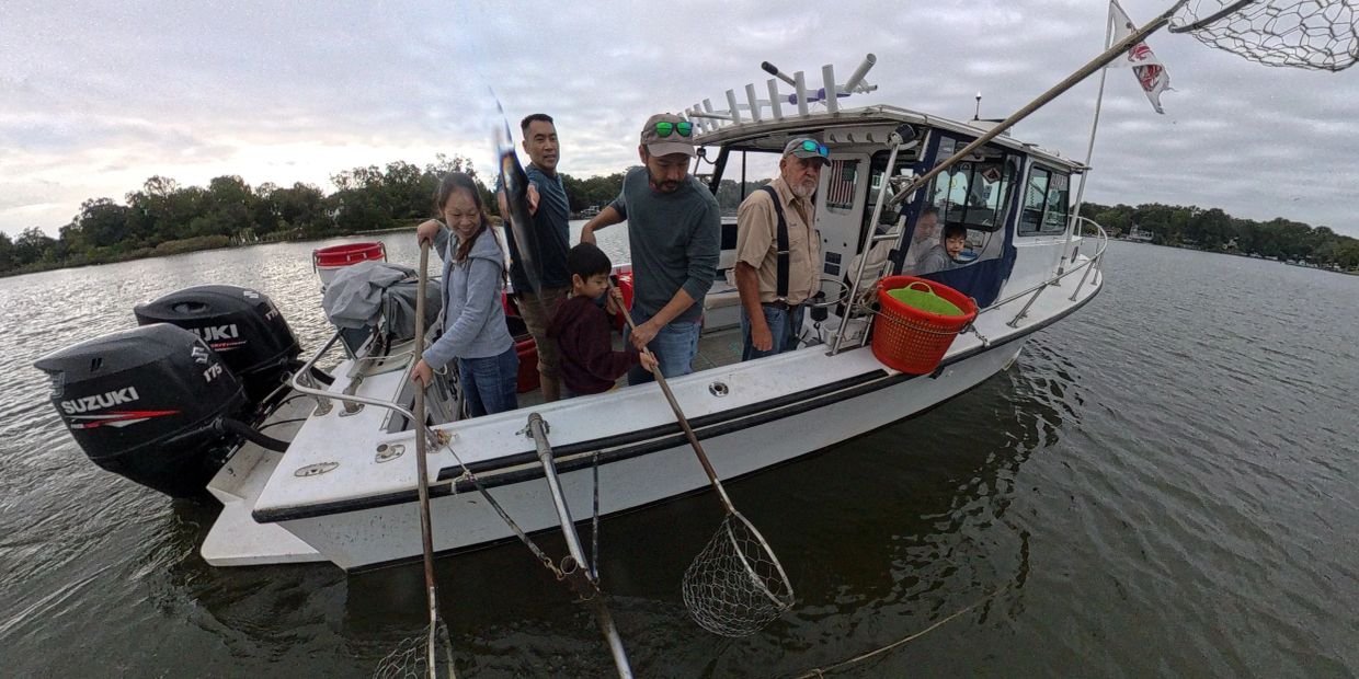 Group fishing on a boat with nets and a caught fish.