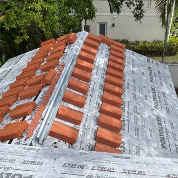 Roof installation with terracotta tiles being laid on a waterproof underlayment.