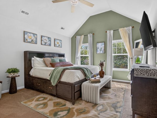 Cozy bedroom with green accent wall and floral decor.