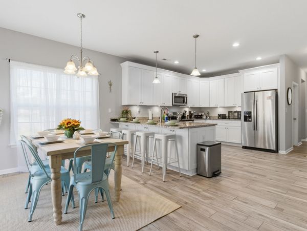 Bright modern kitchen and dining area with white cabinets and blue chairs.