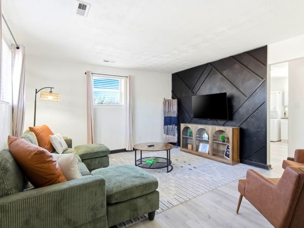 Modern living room with green couch and black accent wall.
