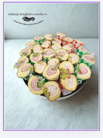 A bowl filled with assorted rolled sandwiches wrapped in colorful paper.