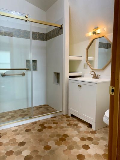 Modern bathroom with hexagonal tile floor and glass shower.