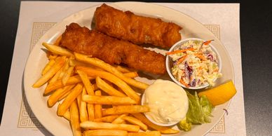 Plate with fried fish, French fries, coleslaw, tartar sauce, and a lemon wedge.