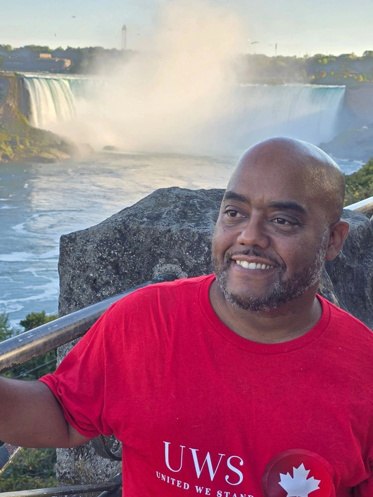 Man in red UWS shirt smiling near Niagara Falls.