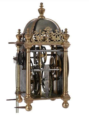 Antique brass clock mechanism with gears and decorative elements.