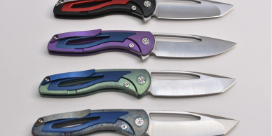 Four colorful folding knives with metal blades arranged horizontally on a white surface.