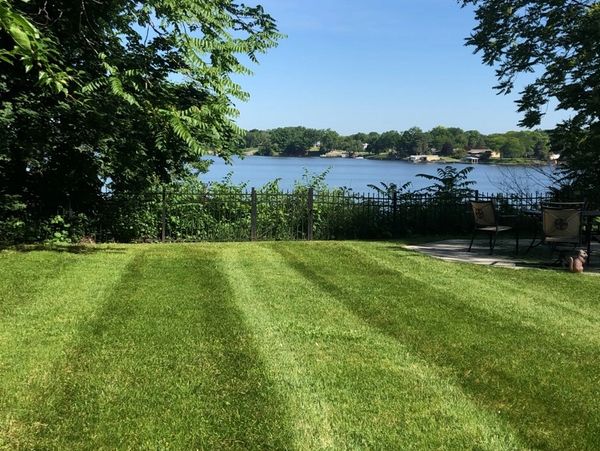 Freshly mowed lawn overlooking a peaceful lake on a sunny day.