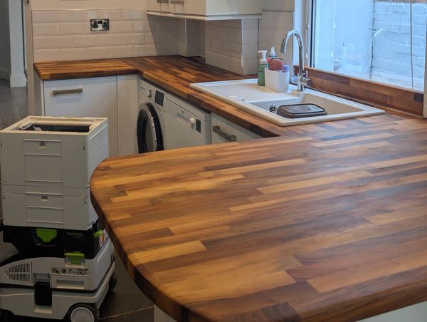 Modern kitchen with wooden countertops and white cabinets under warm lighting.