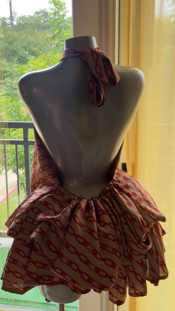 Back view of a mannequin wearing a stylish, patterned halter dress with ruffles.