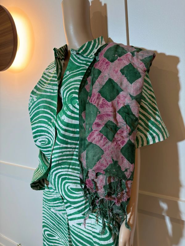 Mannequin dressed in a green and white patterned outfit with a pink and green scarf.