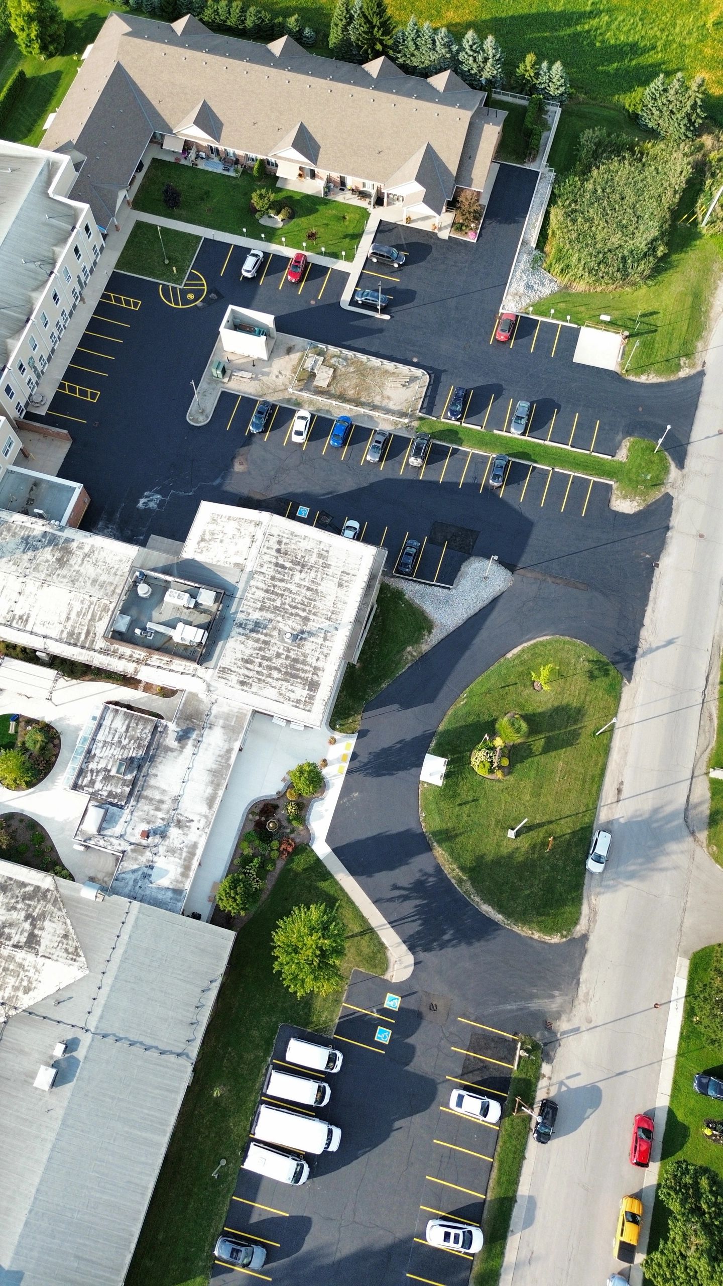 Aerial view of a parking lot with cars and buildings surrounded by greenery.