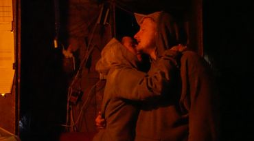 Two soldiers embrace while under attack.