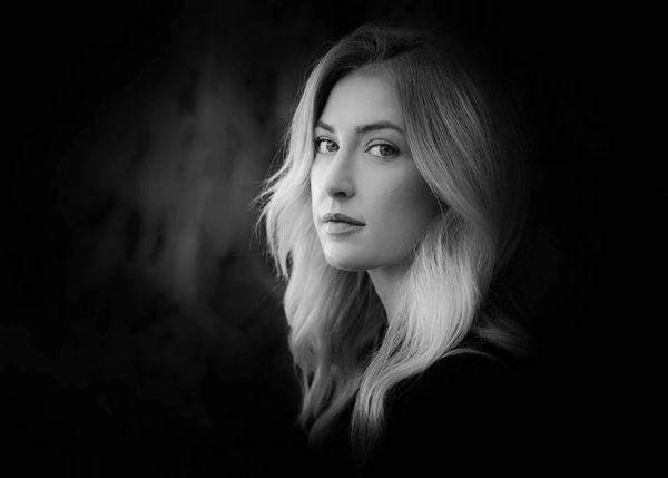 Black and white portrait of a woman with flowing hair gazing thoughtfully.