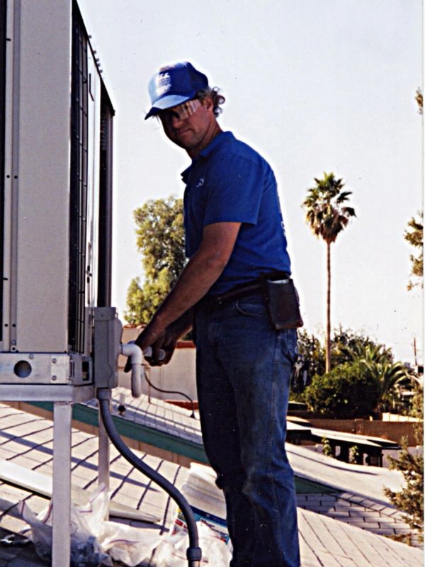 A worker inspecting an outdoor HVAC unit.