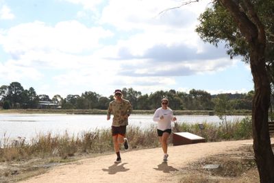 Two people jogging on a lakeside path on a cloudy day.