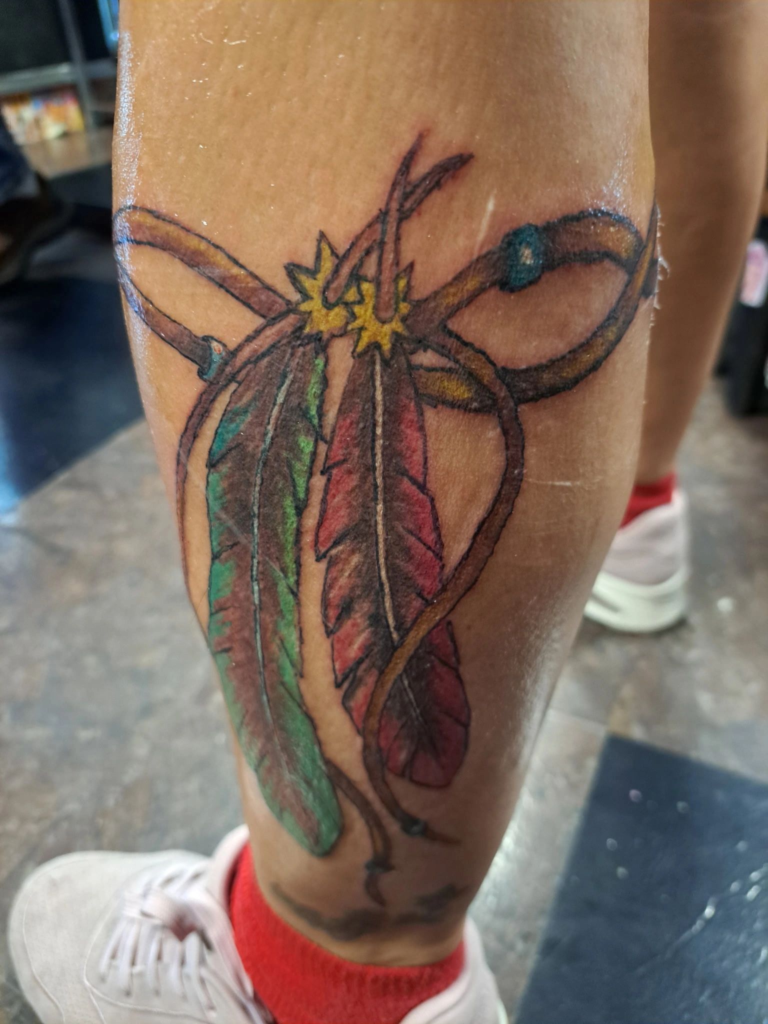 Tattoo of colorful feathers tied together with a string