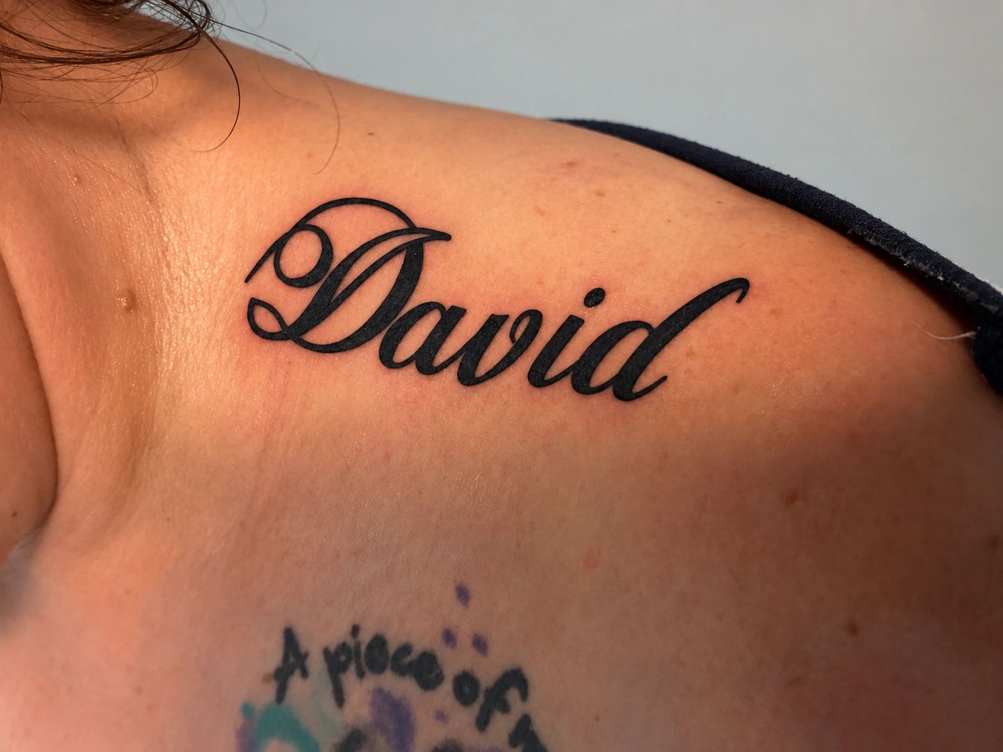 Tattoo of the name 'David' on a shoulder