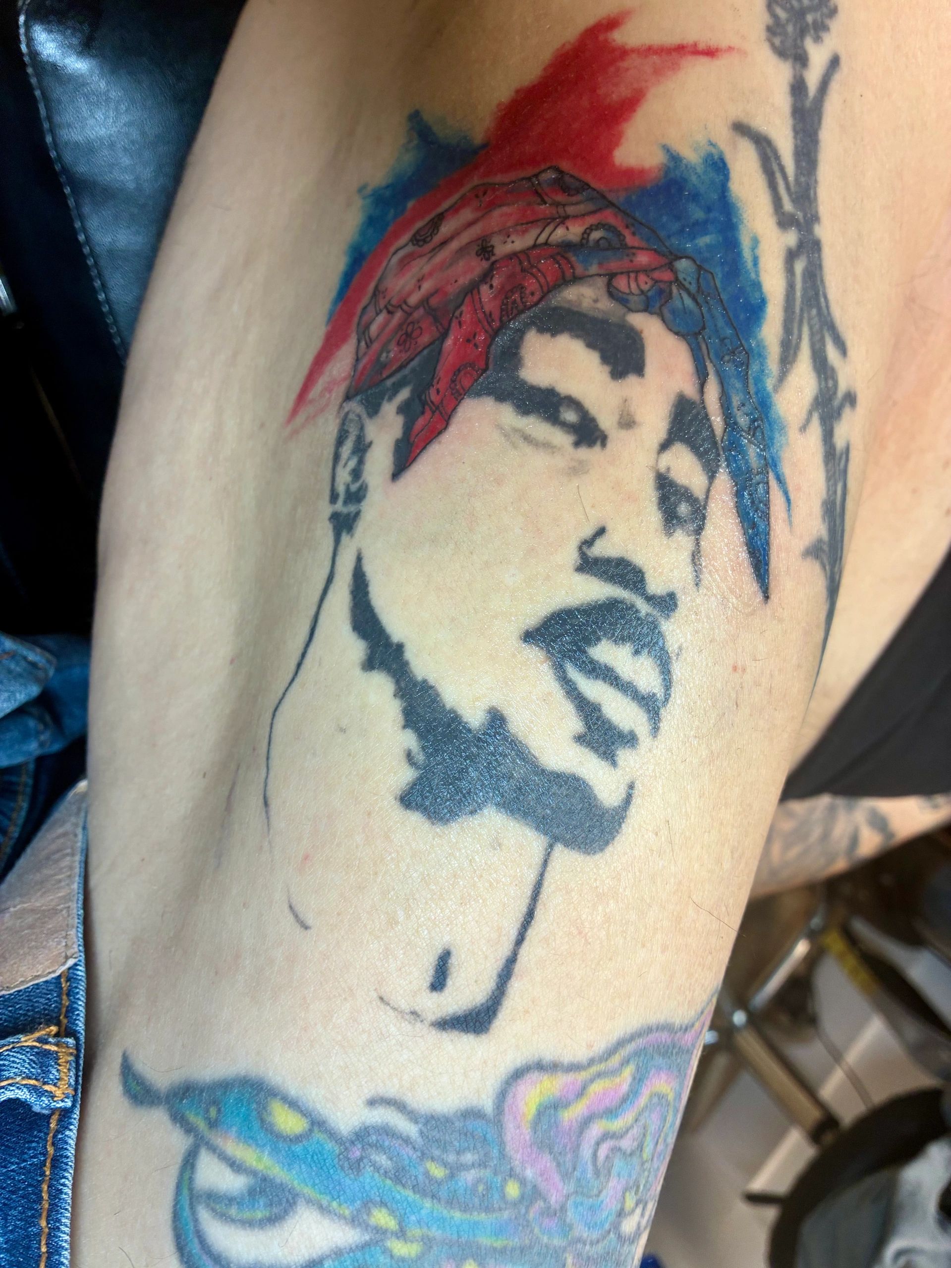 Tattoo of a woman's face with a red and blue bandana