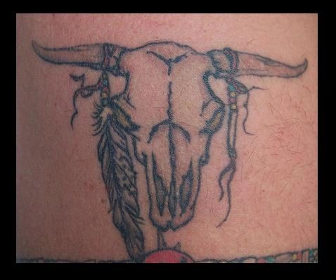 Tattoo of a bull skull with feathers and ribbons
