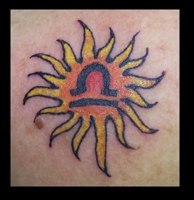 Tattoo of a sun with a Libra zodiac symbol inside