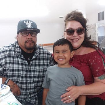 Family photo with a man, woman, and smiling child indoors.