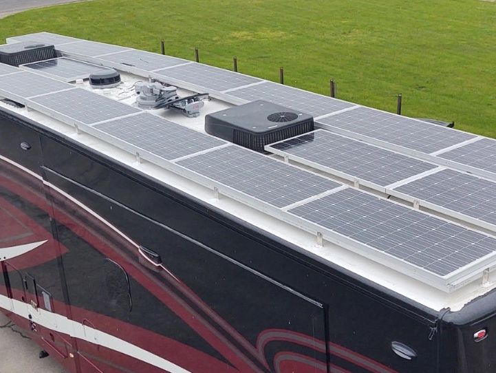 multiple solar panels on top of an RV parked in a lot.
