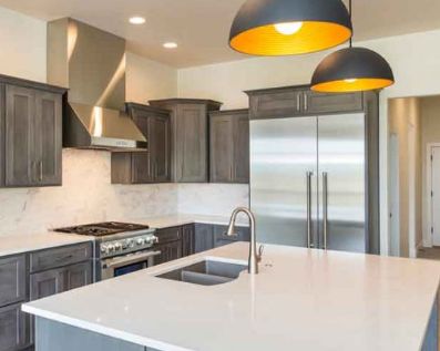 Kitchen remodel featuring industrial lighting and custom cabinets and solid surface countertops