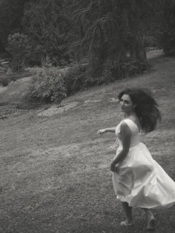 Woman in a white dress spinning outdoors.