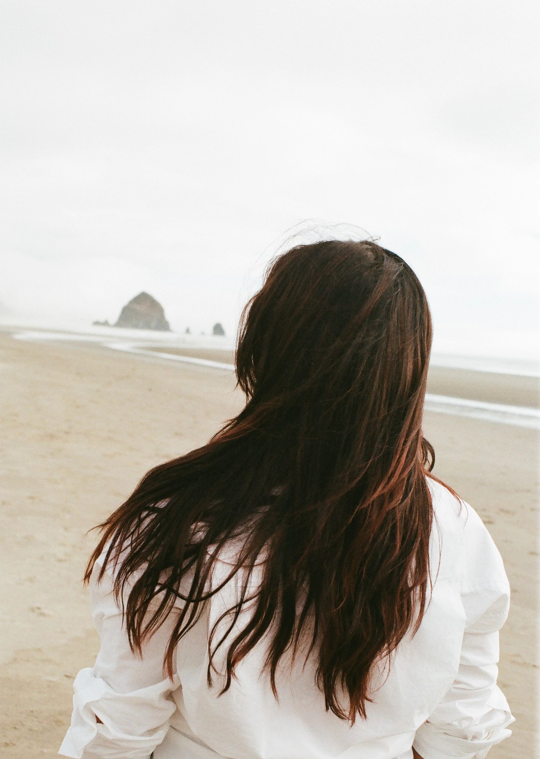 Woman with long hair on a deserted beach.