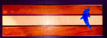 Wooden board with alternating light and dark stripes, featuring a blue dolphin figure on the right.