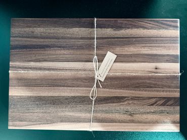 A wooden cutting board tied with string and a small tag.