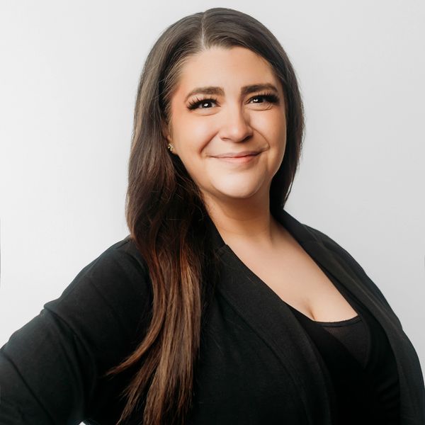 Smiling woman with long dark hair wearing black attire.