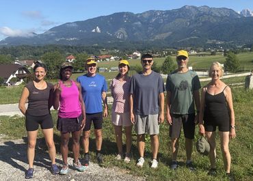 Group of seven people outdoors with mountains in the background.