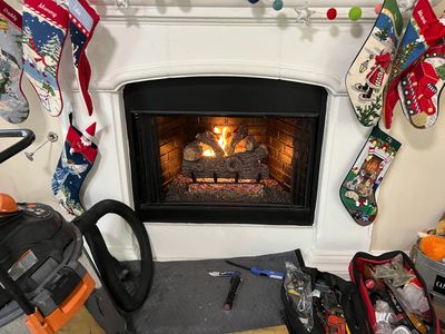 Wood burning inside fireplace with Christmas stockings hanging around