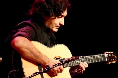 Man passionately playing an acoustic guitar on stage.