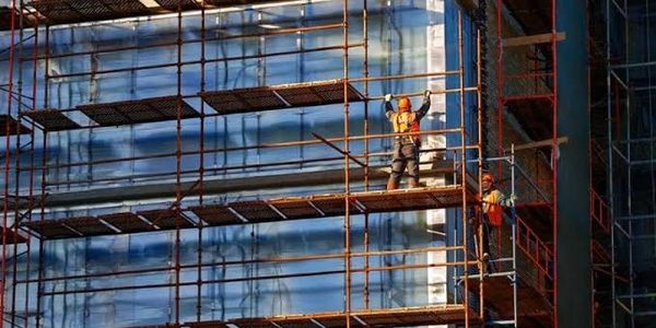 Construction workers on scaffolding working on a building facade.